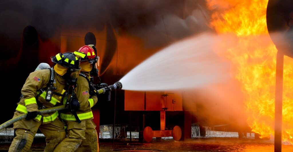 two firefighters fighting blaze with water