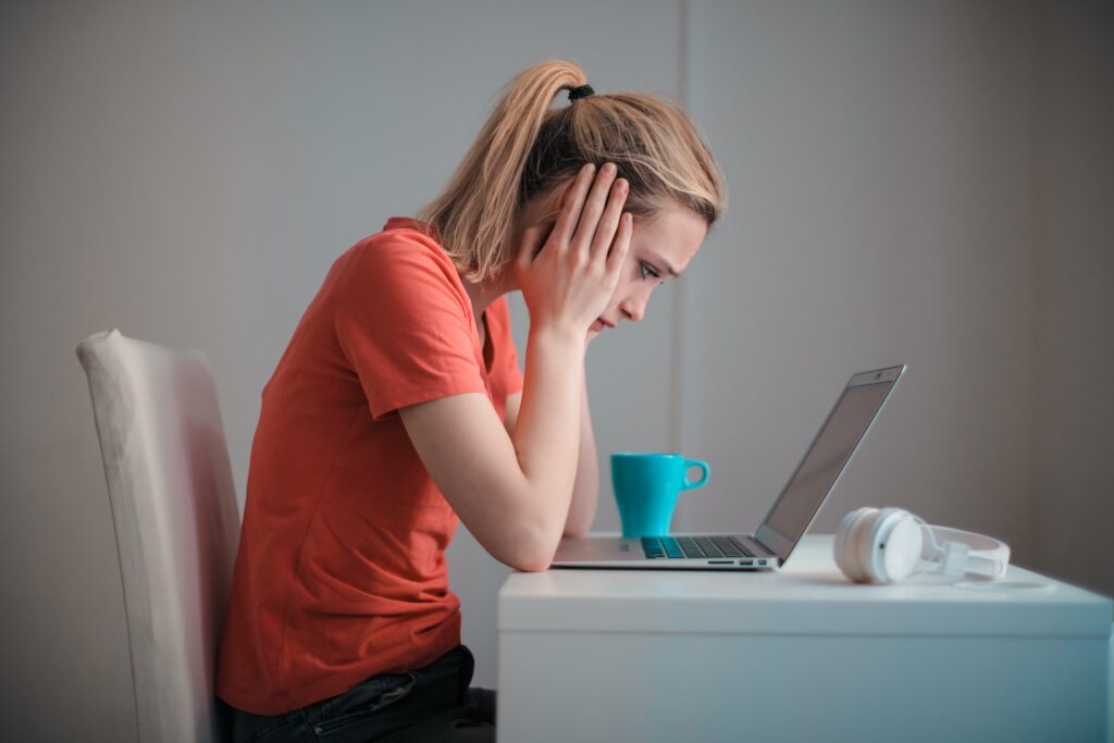 woman holding her head at a desk