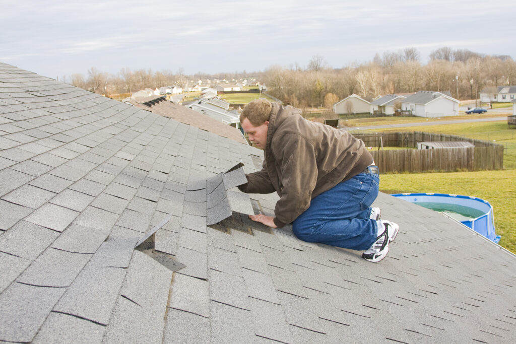 man working on lifted shingles