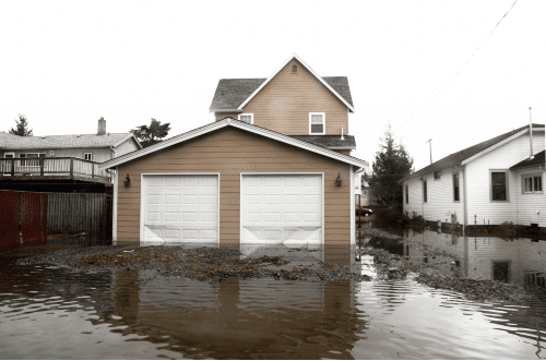 flood waters covering bottom of tan house's garage