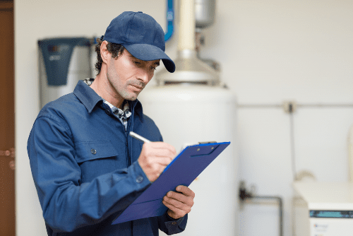 man wearing blue uniform writing inspection notes on clipboard