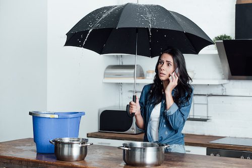 woman in kitchen under black umbrella on the phone