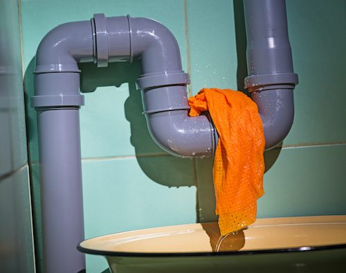 leaking gray plastic pipe wrapped with orange cloth