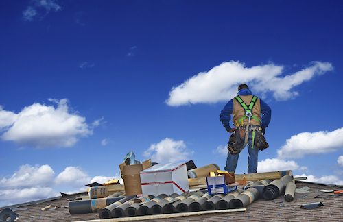 Roof Worker standing on roof next to supplies