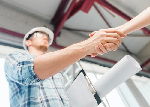 storm repair contractor with blueprint shaking partner hand